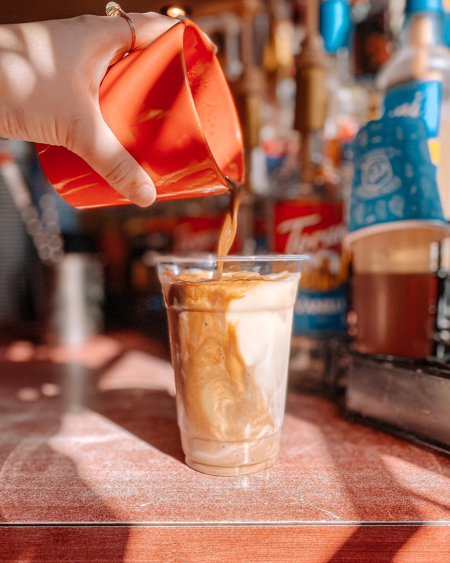 Barista pouring espresso over iced milk